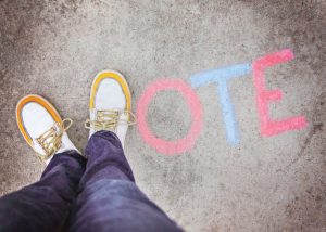 a pair of shoes in the form of the letter V for vote on a sidewalk toned with a retro vintage instagram filter